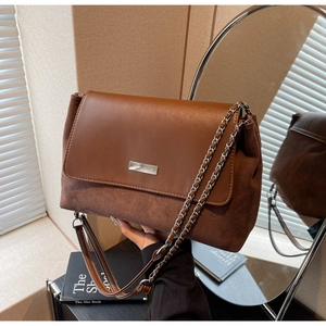 Detail der Schultertasche aus Leder und Wildleder mit Metalllogo und Kettenriemen