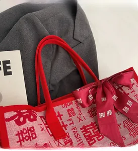 Close-up of red woven wedding tote with Xi patterns and ribbon bow detail