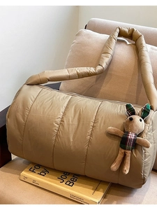 Quilted khaki puffer shoulder bag with cute rabbit pendant on a cozy sofa setting