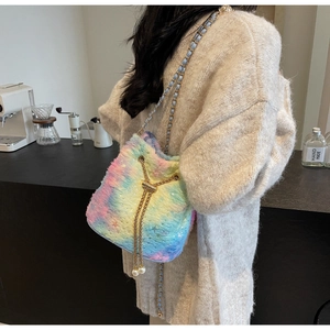 Rainbow plush bucket bag with gold chain and pearl drawstring shown on a model