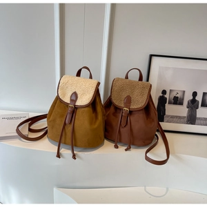 Detail of vintage suede backpacks with faux shearling trim and drawstring buckle closure