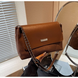Detail der braunen Schultertasche mit Wildleder-Patchwork, Metalllogo und Kettenriemen
