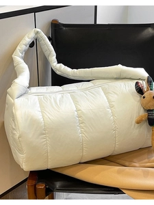 Quilted white puffer cylinder bag with plush rabbit charm and padded shoulder strap