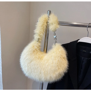 Détail de la texture en fausse fourrure et de la chaîne à cœur sur le sac hobo jaune pâle