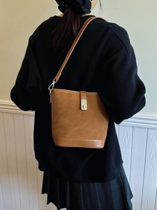Vintage brown suede and leather bucket bag with gold clasp shown on a model