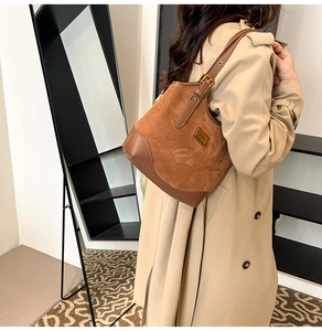 Detailansicht der braunen Bucket-Bag aus Wildleder-Patchwork mit goldenem Logo-Schild