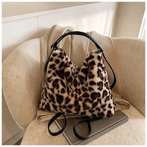 Détail du sac cabas en fausse fourrure léopard avec anses en cuir noir sur un canapé