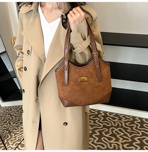 Detailansicht der braunen Vintage-Wildledertasche mit Lederbesatz und goldener Metallplatte