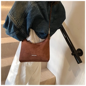 Detail der braunen Wildledertasche mit silberner Metallleiste und elegantem Retro-Stil