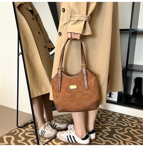 Details der Vintage-Tasche mit braunem Wildleder-Patchwork und goldener Metallplakette