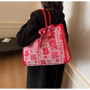 Detailed side view of a large red wedding tote bag with double happiness patterns and bow