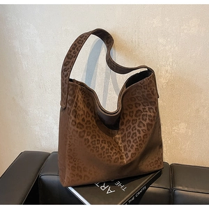 Detailed close-up of a large leopard print hobo bag on a black leather bench