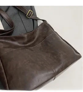 Detailed close-up of dark brown vintage leather tote bag with adjustable gold buckle strap
