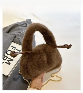 Detailed close-up of brown faux fur handbag featuring gold chain and leather drawstring knot