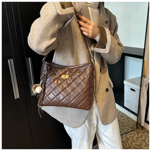 Gros plan du sac seau marron en cuir matelassé avec fermoir doré et pendentif décoratif