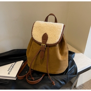 Detail view of the brown faux suede backpack featuring cream faux shearling flap and gold hardware