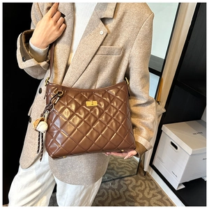 Sac bandoulière marron matelassé avec fermoir doré et breloque baseball sur mannequin