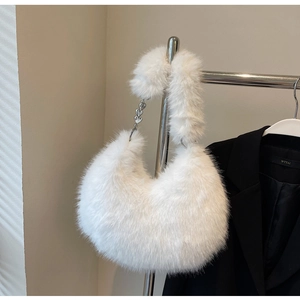 Gros plan du sac à bandoulière en fausse fourrure blanche avec chaîne argentée à cœurs