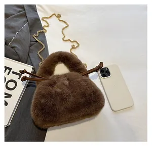 Brown plush handbag with gold chain shown next to a smartphone for size scale