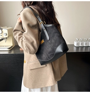Detail der schwarzen Schultertasche aus Wildleder und Leder mit goldener Schnalle