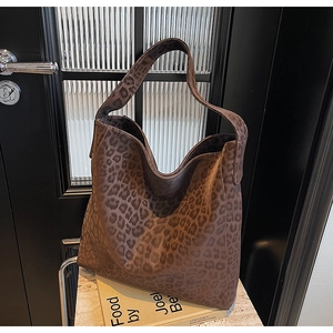 Detailed close-up of a brown leopard print tote bag with a wide shoulder strap design