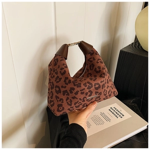 Detailansicht einer Handtasche mit Leopardenmuster, braunen Griffen und Goldakzenten