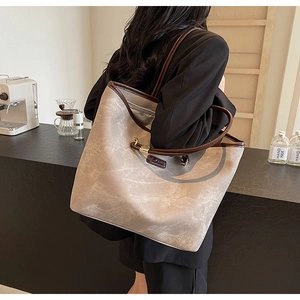 Detail view of large tote bag with retro texture and brown leather trim in cafe setting