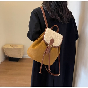 Rear view of a model wearing a yellow suede backpack with white faux shearling detail