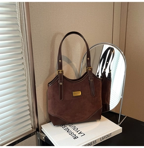 Detailansicht der kaffeebraunen Wildleder-Tragetasche mit Lederbesatz und goldenem Logo