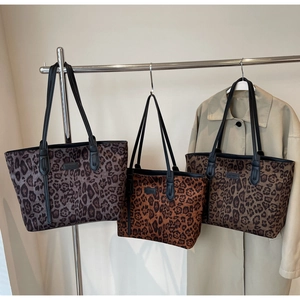 Multiple stylish leopard print tote bags with black straps hanging on a metal rack