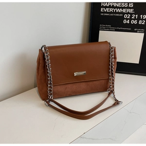 Detail der Schultertasche aus braunem Leder und Wildleder mit Kette und Metallschild