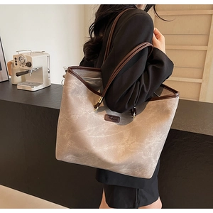 Detail view of large grey tote bag with brown leather handles and marble texture surface
