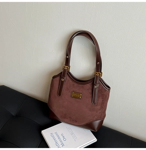 Nahaufnahme der braunen Wildleder-Tragetasche mit Goldlogo und Schnallendetail