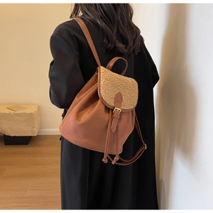 Detail of brown suede and shearling backpack with leather buckle and drawstring closure