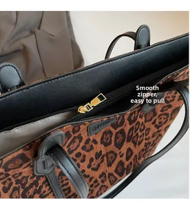 Detailed view of the smooth metal zipper and leopard print fabric on a shoulder bag