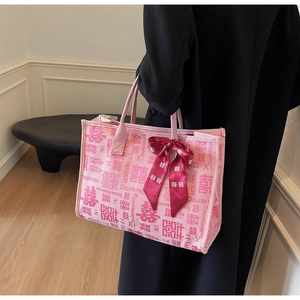 Close-up of pink canvas tote bag featuring double happiness prints and red silk ribbon bow