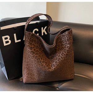 Macro detail of brown leopard print hobo bag showing faux suede texture and wide strap