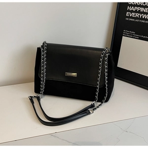 Detail der schwarzen Achseltasche mit Metallkette und YOUBER-Schnalle auf Marmorfläche