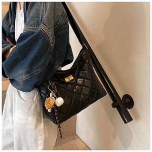 Détail du sac seau noir matelassé avec fermoir doré et breloque gant de baseball