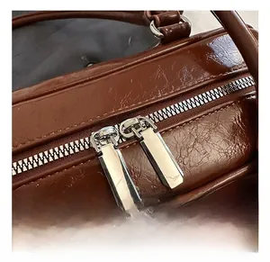 Détails des doubles fermetures éclair argentées sur sac en cuir marron brillant