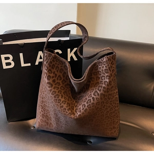 Detail of a brown leopard print tote bag with soft texture on a black leather sofa