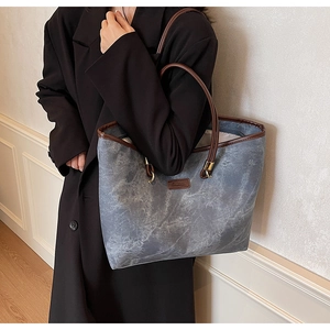 Detail of blue-grey marble texture tote bag with brown leather handles worn by a model