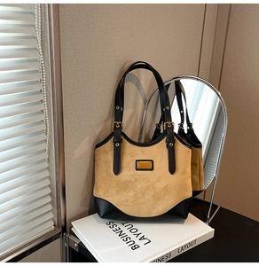 Detailaufnahme der braunen Wildleder-Tote Bag mit schwarzen Ledergriffen und Goldakzenten