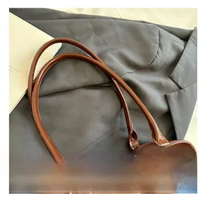 Détails du sac à bandoulière en cuir verni marron avec anneaux argentés et fermeture éclair