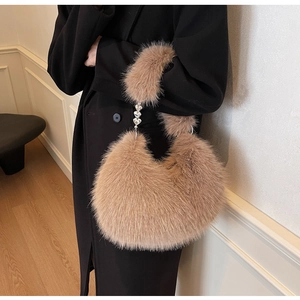 Détail du sac à main en fausse fourrure camel avec chaîne métallique en forme de cœur argenté