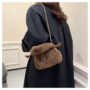 Detail of plush brown bucket bag with gold chain strap on black winter coat