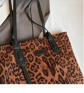 Close-up of leopard print tote bag with black leather straps and brand logo patch
