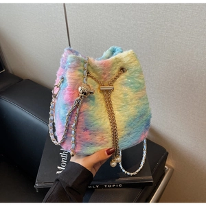 Detailed shot of plush bucket bag featuring gold chain strap and pearl drawstring charms