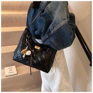 Détail du sac seau noir matelassé avec boucle dorée et breloques de baseball