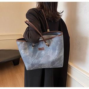 Detail of grey marble pattern tote bag with brown leather handles worn by a model